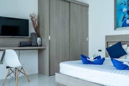 Modern bedroom with a wall-mounted TV, workspace, and stylish decor