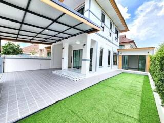 Exterior view of a modern two-story house with a carport and a neatly maintained lawn