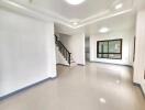 Spacious modern living room with tiled flooring and staircase