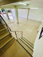Staircase leading to a spacious, empty room with a glossy floor and large window