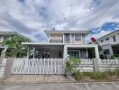 Front view of a modern two-story house with a white fence