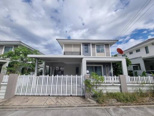 Front view of a modern two-story house with a white fence