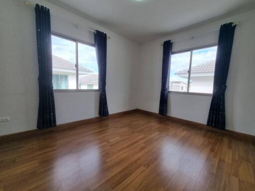 Spacious bedroom with wooden flooring and large windows