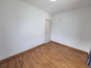 Empty bedroom with wooden flooring and white walls