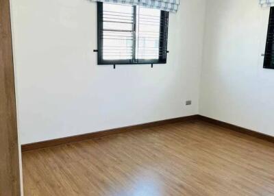 Empty bedroom with wooden floor and two windows