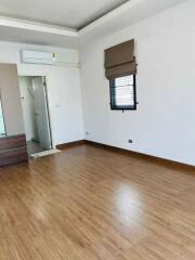 Spacious bedroom with wooden flooring, air conditioning, and a view of the bathroom entrance