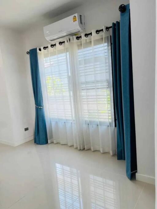 Bedroom with large window, blue curtains, and air conditioner