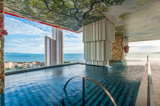 Infinity pool with a scenic view of the ocean and city buildings