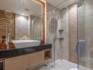 Modern bathroom with glass shower, black counter, and illuminated mirror