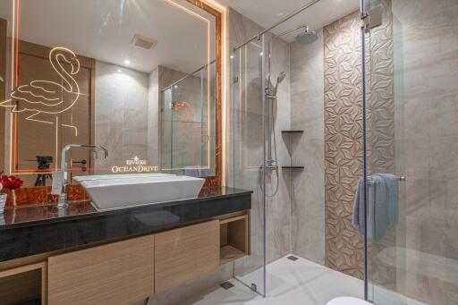 Modern bathroom with glass shower, black counter, and illuminated mirror