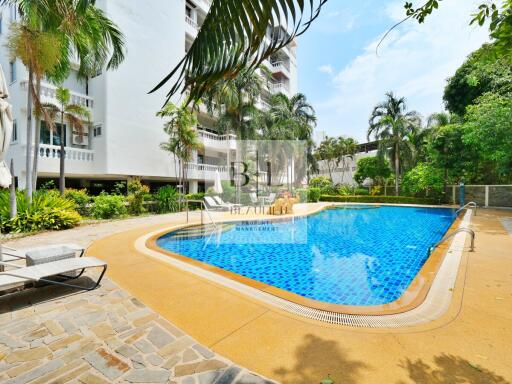 Swimming pool area with deck chairs and surrounding greenery at a residential building