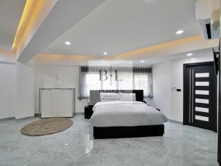 Modern bedroom with marble flooring, ceiling lights, and a large bed