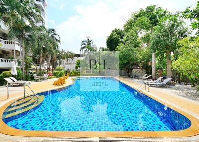 Outdoor swimming pool area with lounge chairs and lush greenery