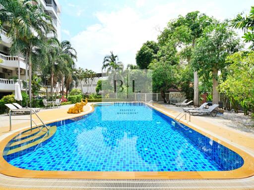 Outdoor swimming pool area with lounge chairs and lush greenery