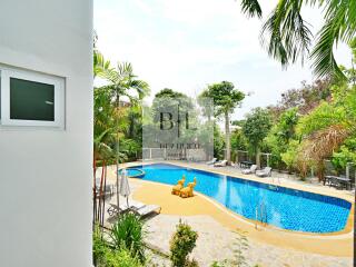 Swimming pool area with lounge chairs and greenery