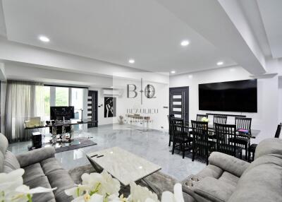 Modern living room with open layout, large TV, dining table, and gray sofas