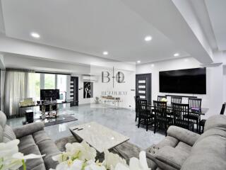 Modern living room with open layout, large TV, dining table, and gray sofas