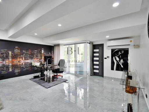 Modern living room with cityscape wall art, glass desk, and large sliding door