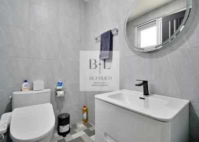 Modern bathroom with toilet, sink, mirror, and stylish grey tiles