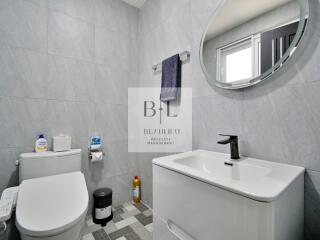 Modern bathroom with toilet, sink, mirror, and stylish grey tiles