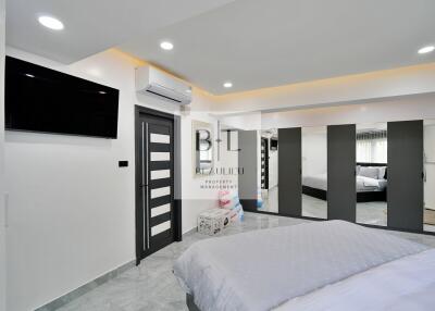 Modern bedroom with bed, television, air conditioning, and large wardrobe