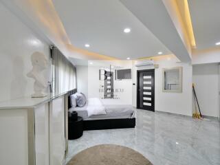 Modern bedroom with grey bed, marble flooring, and ceiling lights