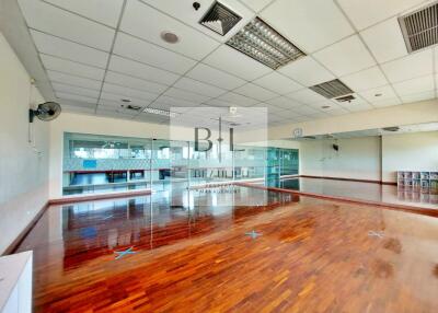 Spacious open floor area with wooden flooring and large mirrors