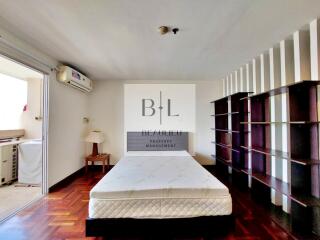 Spacious bedroom with hardwood floor, built-in shelves, and natural lighting.