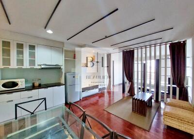 Modern kitchen and living area with dining table, refrigerator, and microwave.