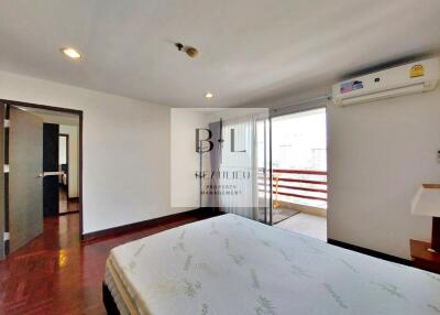Spacious bedroom with wooden flooring and access to a balcony