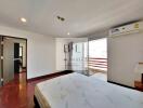 Spacious bedroom with wooden flooring and access to a balcony