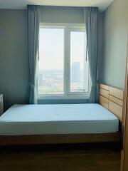 A bedroom with a large window, bed, and chest of drawers