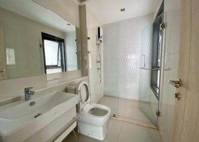 Modern bathroom with large mirror, sink, toilet, and glass-enclosed shower