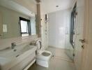 Modern bathroom with large mirror, sink, toilet, and glass-enclosed shower