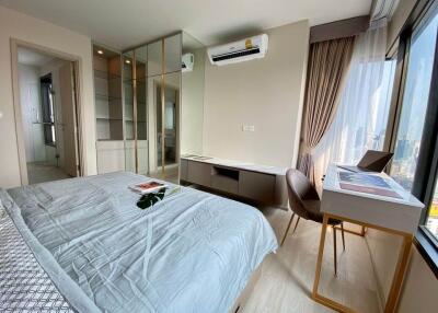 Modern bedroom with city view, bed, desk, chair, air conditioner, and built-in wardrobe