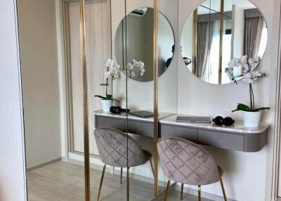 Modern bedroom vanity with a round mirror and upholstered chair