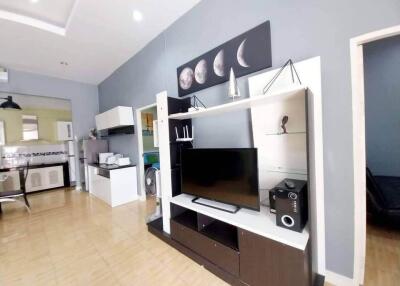 Modern living room with entertainment center and kitchen in the background