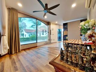 Spacious living room with large windows and ceiling fan