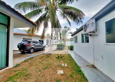 View of an outdoor space with a coconut tree, a house exterior, and a parked car