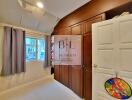 Bedroom with a window, wooden closet, and white door