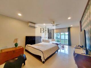 Spacious and well-lit bedroom with a large bed, air conditioning, and a balcony view.