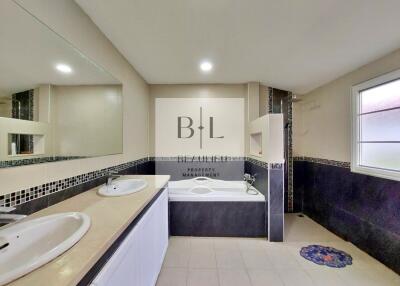 Spacious bathroom with large mirror, dual sinks, and bathtub
