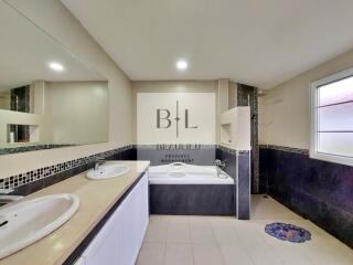 Spacious bathroom with large mirror, dual sinks, and bathtub