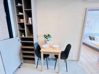 Compact dining area with built-in shelving and view into bedroom