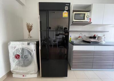 Modern kitchen with black refrigerator, washing machine, and microwave