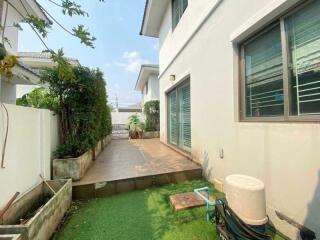 Side yard of a house with garden and tiled patio area