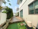 Side yard of a house with garden and tiled patio area