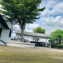 Spacious outdoor area with trees, parking, and a satellite dish