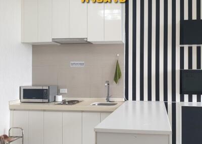 Modern kitchen with white cabinetry, countertop, and striped black and white wall design