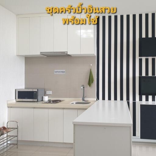 Modern kitchen with white cabinetry, countertop, and striped black and white wall design